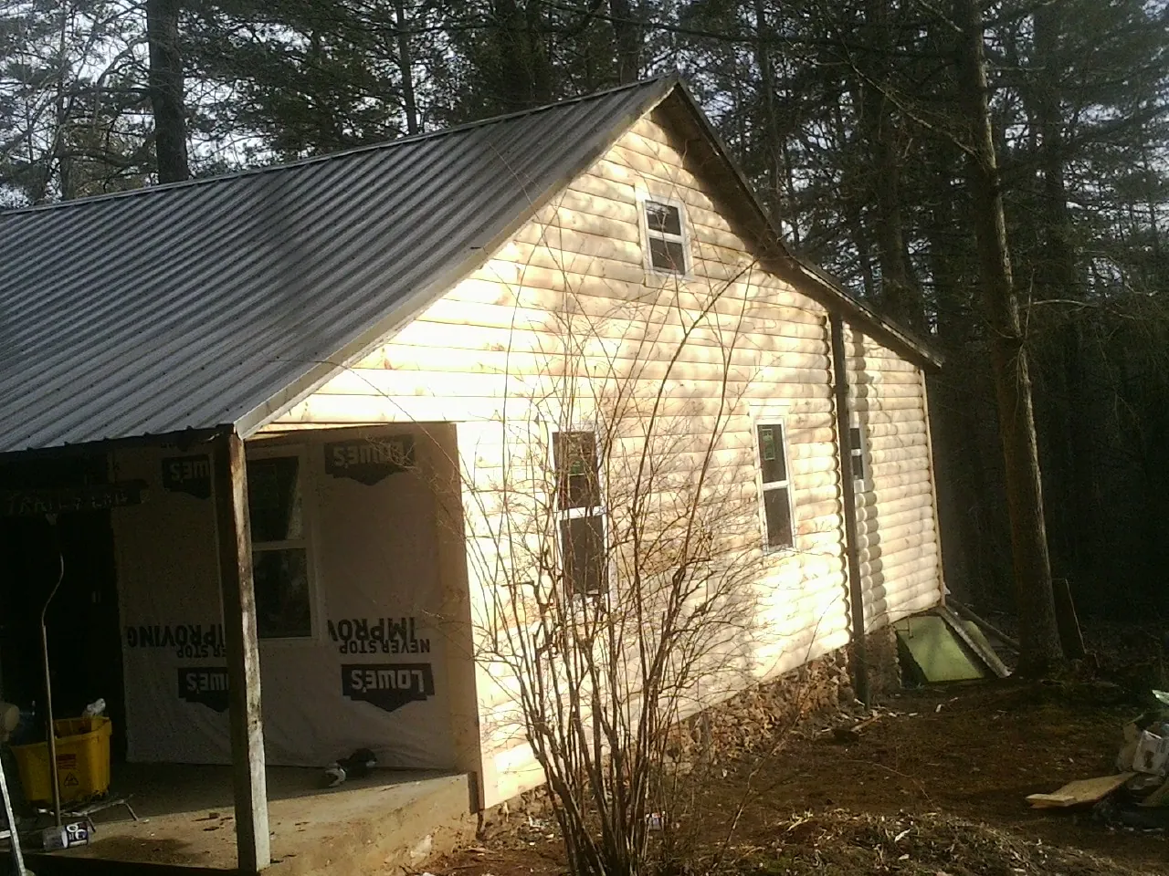 Log siding gable end under a dark metal roof edge in Beulah
